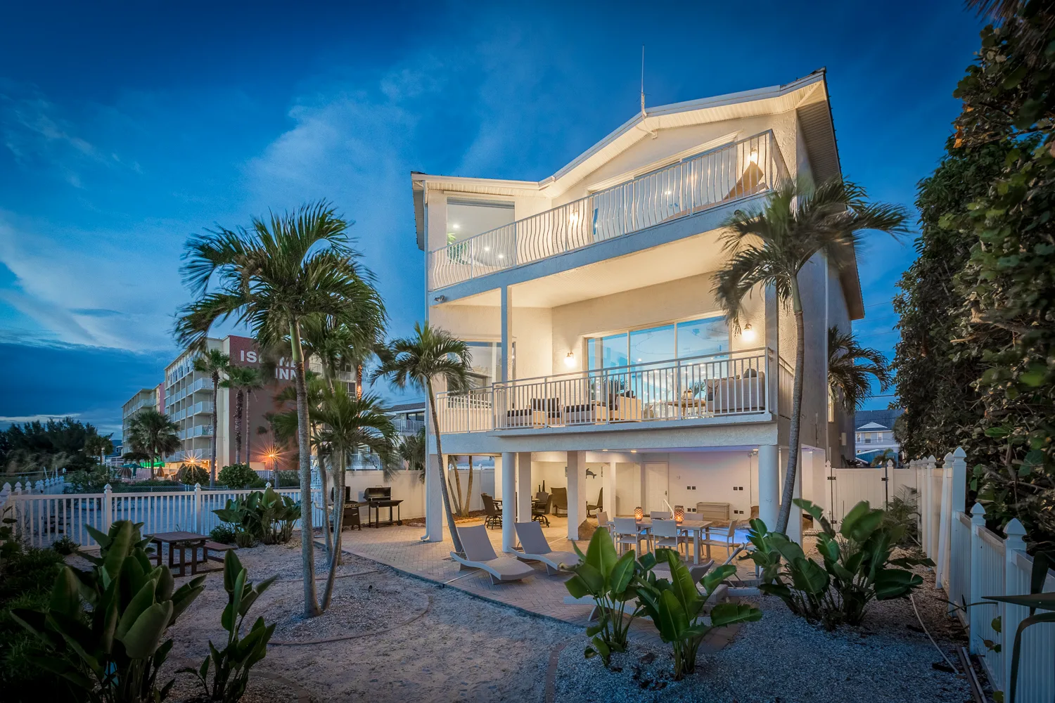 Multi-level Florida beach house at golden hour surrounded by palms