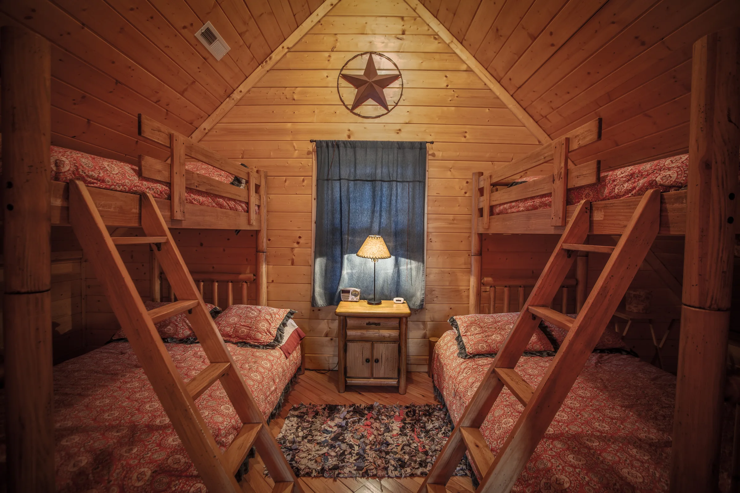 Knotty pine bunk room with two bunk beds, ladders and star accent