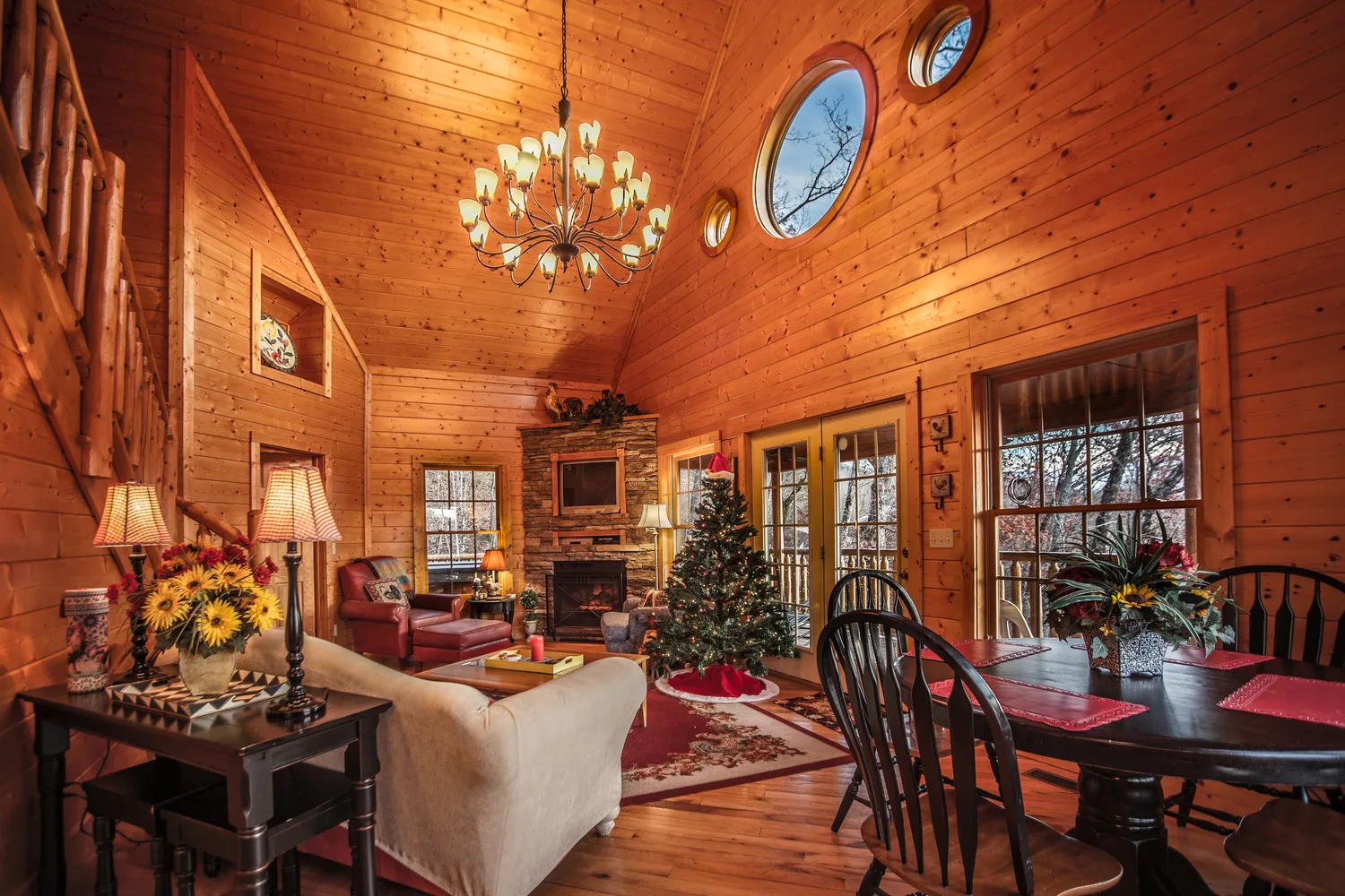 Warm wood chalet living room with chandelier, stone fireplace and Christmas tree