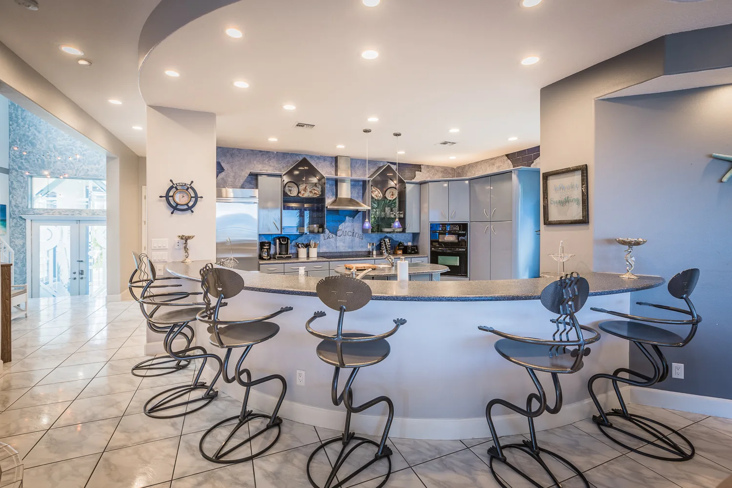 Open kitchen with curved breakfast bar and whimsical wrought-iron stools